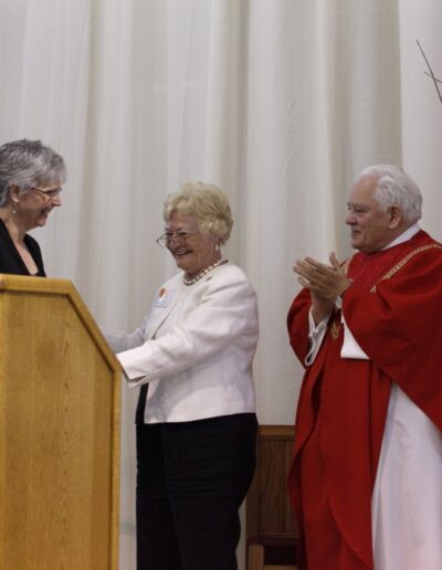 Mrs. Joan Troy accepts congratulations from Mrs. Anne Stahel and Msgr. Gerald L. Lewis, at a ceremony held at Cardinal Gibbons High School